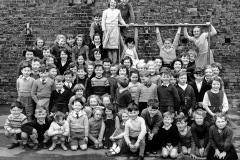 The climbing frame at Eastrington and children in 1960
Front row, from left: Peter Wraith, Ian Young, Carol Hopkinson, Jimmy Wraith, Linda Flint, Lynn Johnson, Anne Chapman, Colin Wraith, Herbert Lowther, Charlie Chapman, Stephen Clark, Pamela Atkinson, Susan Naylor.
Second row, from left: Stephen Cammidge, Stuart Young, Andrew White, Tony Ingram, Robin Watson, John Benson, Maureen Wraith, Elaine Anson, Doris Crowcroft, unknown [turning round], May Lowther, Frankie Johnson, Eddie Crowcroft, Susan Watson, John Railton, Albert Clark, Garry Westoby, Stephen Dent, Angela Wiles [with pinafore]
Third row, from left: Lynn Harrison, Judith Lilley, Sandra Jackson [just in front of Judith], Marion Chapman, unknown girl, Janet Hopkinson, Linda Anson, Brian Malcolmson, David Lilley, Peter Wilburn, Norma Robinson, Vivienne Howden [with hair slide], Pauline Wraith, Elizabeth Anson, Bernice Wraith [behind Elizabeth and in front of 'Laddy' Lowther]
Fourth [back] row, from left: Valerie Johnson, Shirley Clark, Graham Harrison, Jackie Railton, Carmella Grande [with pigtails], Doreen Robinson, behind her Kathleen Malcolmson, Keith Holmes [behind Kathleen], Phyllis Brown [standing on bars], John Kirk, Mary Clark [hanging left from bar], Gladstone Lowther [hanging, middle], Jean Robinson, Keith Calvert, Freddie Harrison, Kathleen Gaskin.